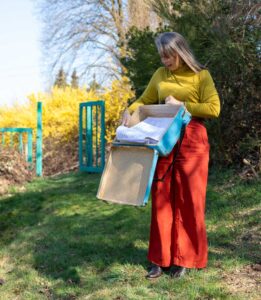 Anna Stijohann steht mit einem Koffer im Garten, der sich geöffnet hat